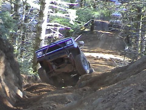 1994 Ford Explorer - Off-road vehicle navigating a challenging dirt trail in a forest setting.