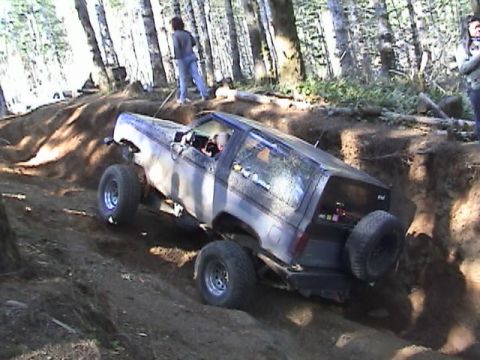1994 Ford Explorer - An off-road SUV navigates a challenging dirt trail in a forest setting.