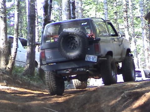 1994 Ford Explorer - A Ford Bronco II navigates an off-road trail with another vehicle partially visible in the background.