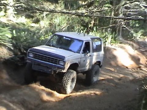 1994 Ford Explorer - This 2-door SUV is navigating a challenging off-road trail with large tires.