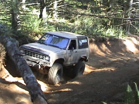 1994 Ford Explorer - Ford Bronco II tackling a challenging off-road trail in a wooded area.