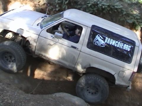 1994 Ford Explorer - A white Ford Bronco II navigates a steep, muddy incline during an off-road excursion.