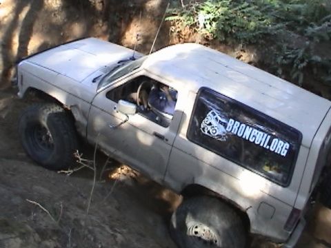 1994 Ford Explorer - A tan Ford Bronco II navigates a challenging off-road trail with large tires.
