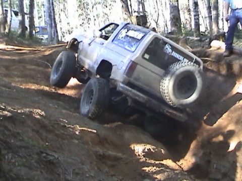 1994 Ford Explorer - An off-road SUV navigates a steep dirt incline, with a Broncoii.org sticker visible on the rear window.