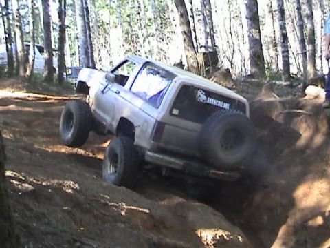 1994 Ford Explorer - Modified SUV navigates a challenging off-road trail with large tires and lifted suspension.