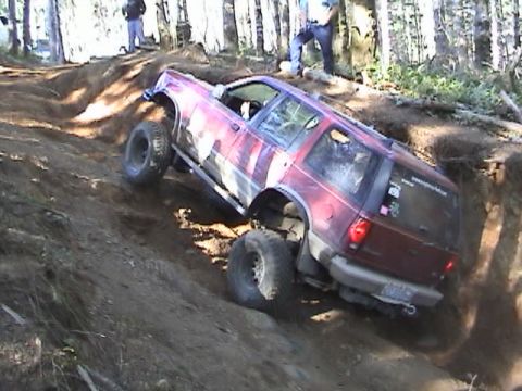 1994 Ford Explorer - Off-road SUV tackling a challenging dirt trail with significant elevation change.