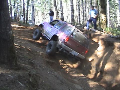 1994 Ford Explorer - An off-road SUV navigates a challenging incline on a wooded trail.