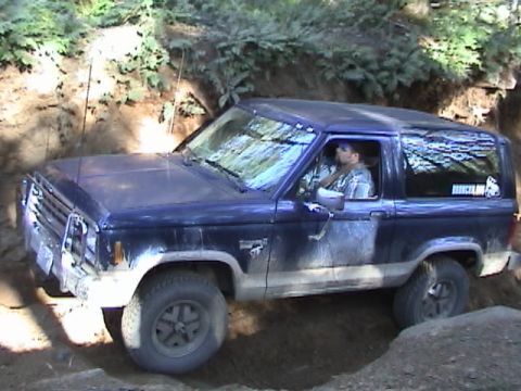 1994 Ford Explorer - A blue Ford Bronco is shown off-roading on a dirt trail.