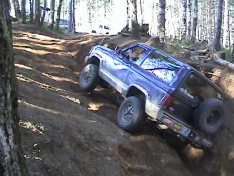 1994 Ford Explorer - An off-road vehicle navigates a challenging dirt incline in a wooded area.