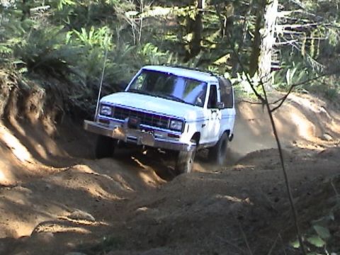 1994 Ford Explorer - White SUV navigates a dusty, wooded trail with a winch mounted on the front bumper.