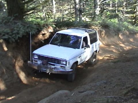 1994 Ford Explorer - White 1990 Ford Bronco II navigates a steep dirt trail during an off-road excursion.
