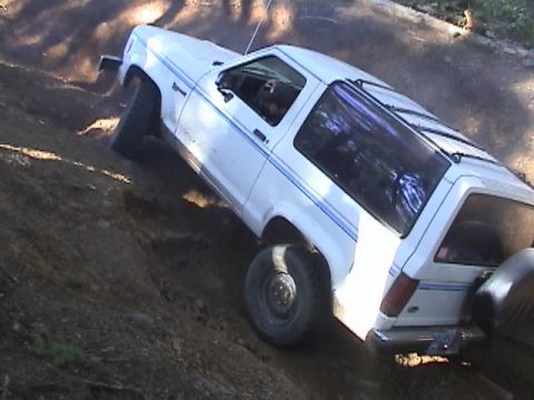 1994 Ford Explorer - A white 1994 Ford Bronco II navigates a steep dirt incline during an off-road excursion.