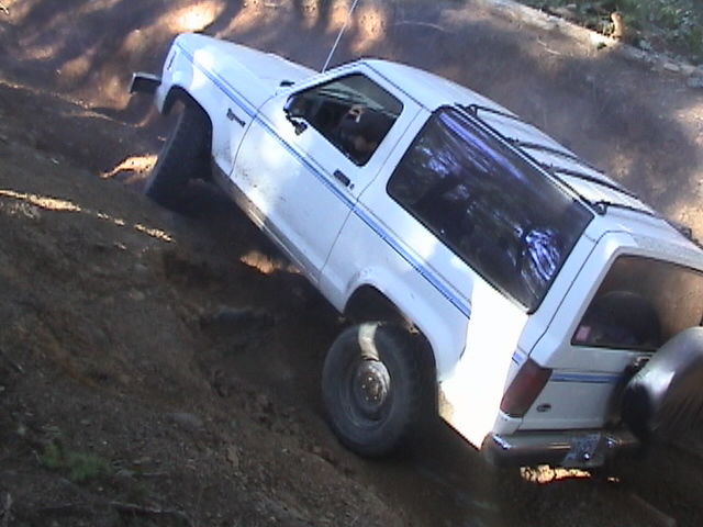 White 1994 Ford Bronco II driving off-road on a dirt hill
