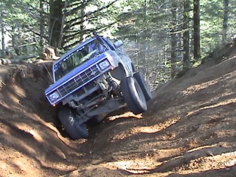 1994 Ford Explorer - Off-road pickup truck navigates a challenging dirt incline, tires digging into the loose soil.