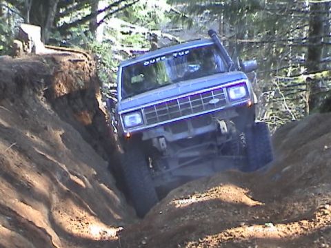 1994 Ford Explorer - A blue off-road SUV navigates a challenging dirt trail with a snorkel and "DUFF TUP" sticker visible.