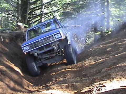 1994 Ford Explorer - Off-road SUV navigates a challenging dirt incline, generating dust and smoke.