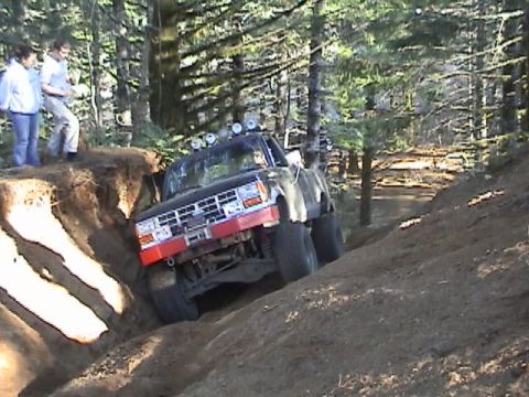 1994 Ford Explorer - Off-road truck navigates a challenging dirt trail in a wooded area.