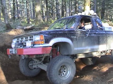 1994 Ford Explorer - Modified Ford Ranger pickup truck navigates a wooded trail with large off-road tires and a custom bumper.