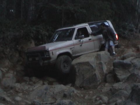 1994 Ford Explorer - A white 1989 Ford Bronco II is shown off-roading over large rocks on a trail.