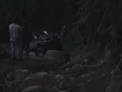 1994 Ford Explorer - An off-road vehicle navigates a challenging rocky terrain in a wooded area.