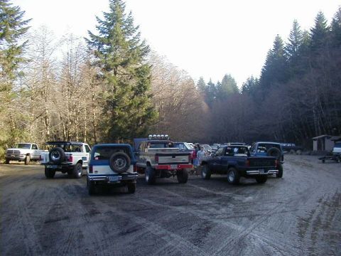 1994 Ford Explorer - A group of SUVs and trucks are parked on a dirt road, possibly at an off-road event or gathering.