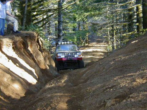 1994 Ford Explorer - A red 1994 Ford Explorer navigates a challenging off-road trail, demonstrating its capabilities on rough terrain.