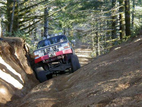 1994 Ford Explorer - An off-road SUV tackles a challenging dirt trail in a wooded area.