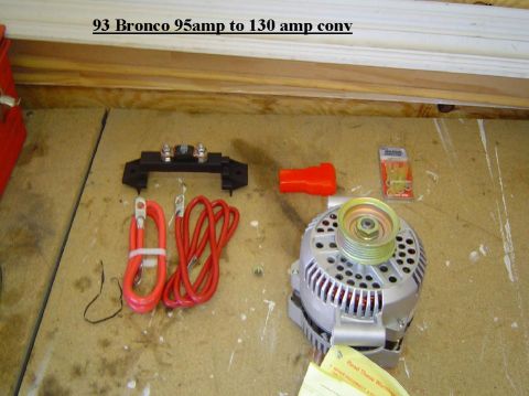 1993 Ford Bronco - Parts laid out on a wooden surface, including an alternator and electrical components.
