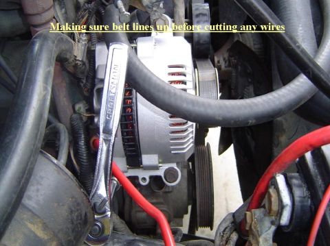 1993 Ford Bronco - Close-up view of engine components, including an alternator and hoses, with a wrench attached.