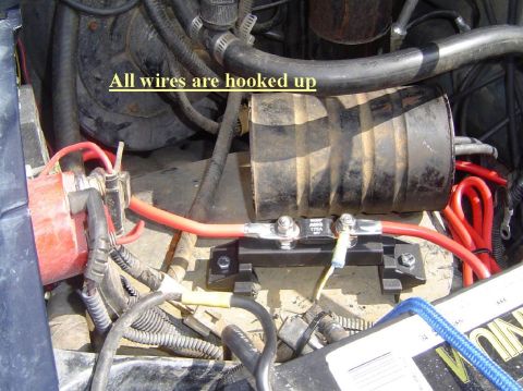 1993 Ford Bronco - Close-up of engine bay wiring, showing red cables and a black fuse block with text.