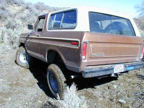 1978 Ford Bronco - A brown 1978 Ford Bronco navigates a dirt trail, showing its rear 3/4 profile.
