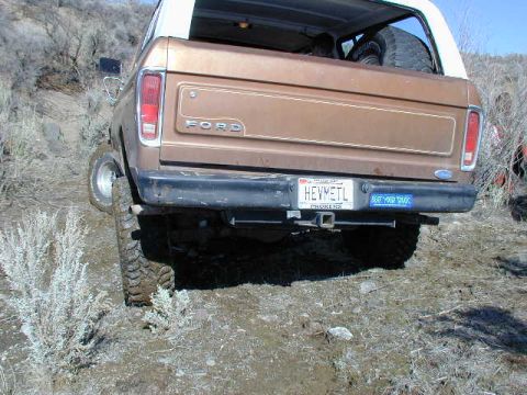 1978 Ford Bronco - Rear view of a 1978 Ford Bronco on a dirt trail with a spare tire inside.