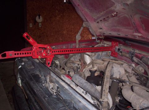 1989 Ford Bronco - A red high-lift jack is placed across the engine compartment of a vehicle.