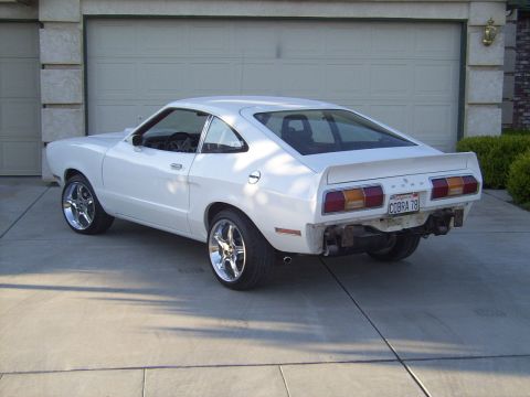 1978 Ford Mustang II - The rear of a white 1978 Ford Mustang II shows a custom spoiler and a license plate reading 'COBRA 78'.