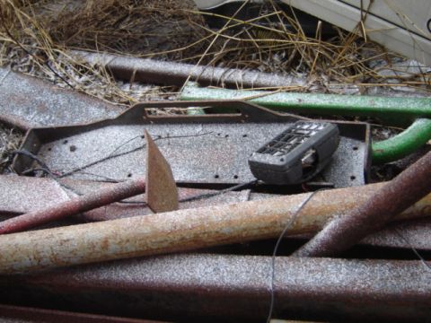 1992 Ford Bronco - A pile of rusty scrap metal and a black electronic device are covered in a light dusting of snow.