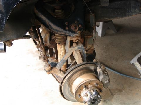 1986 Ford F-150 - Front suspension and brake components are visible, showing signs of rust and wear.