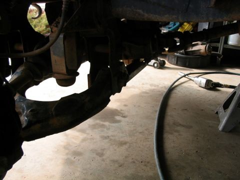 1986 Ford F-150 - Undercarriage view of a truck's suspension system, with tools and equipment nearby.