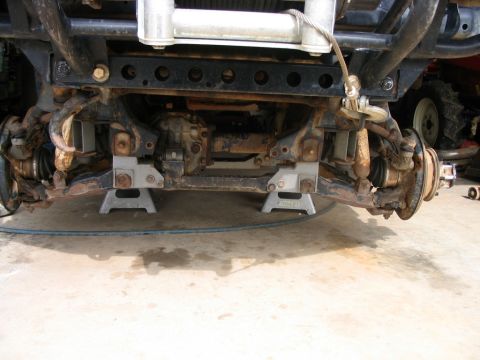 1986 Ford F-150 - The front suspension and undercarriage of a vehicle are visible, supported by jack stands, with a winch mounted above.