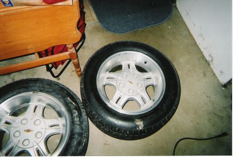 2000 Ford Crown Victoria - Two tires and rims are visible, one with a Chevrolet emblem, resting on a concrete floor.