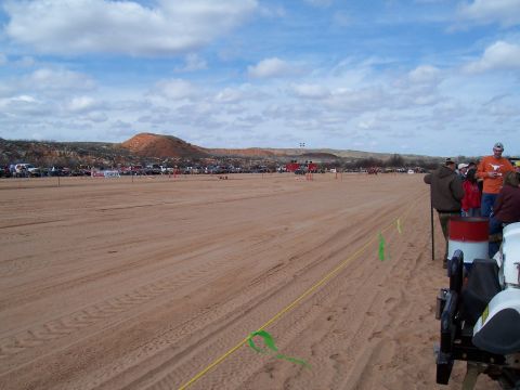 2004 Aston Martin Virage - A wide sandy area with numerous vehicles and spectators gathered for an outdoor event.