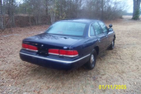 1997 Ford Crown Victoria - Rear view of a dark blue 1997 Ford Crown Victoria parked outdoors on a dirt lot.