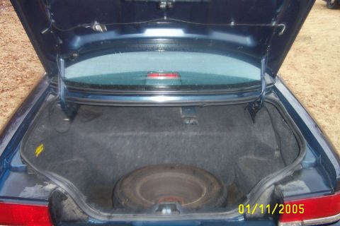 1997 Ford Crown Victoria - The trunk of a dark blue sedan is open, revealing a spare tire and the car's interior lining.