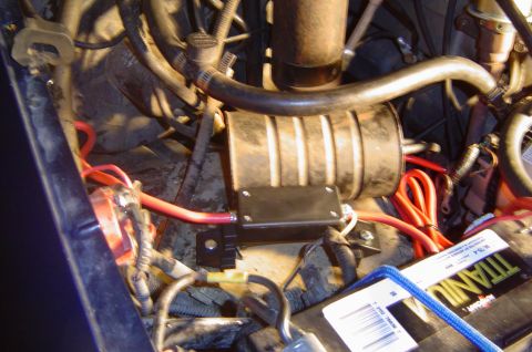 1993 Ford Bronco - Close-up view of engine bay components, including battery and wiring, with a modified cylindrical part.