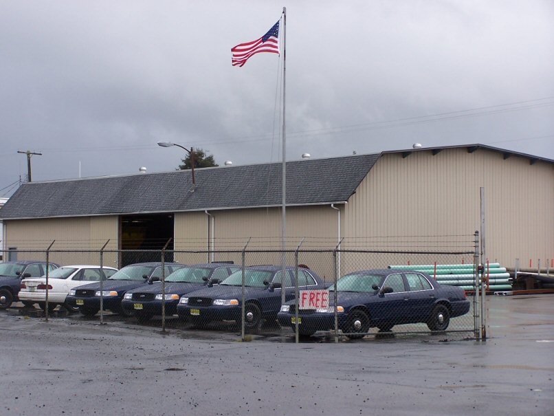 Several dark blue sedans parked in a lot, one with a 'FREE' sign. American flag flies above