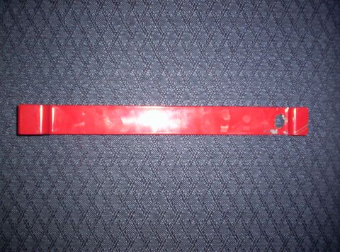 1989 Ford Bronco - A red plastic trim removal tool is shown against a textured blue background.