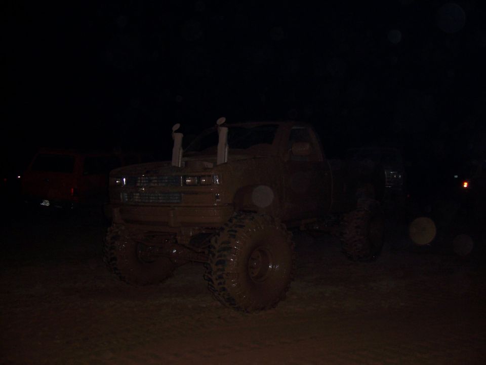 Muddy pickup truck with tall exhaust pipes, another vehicle in background