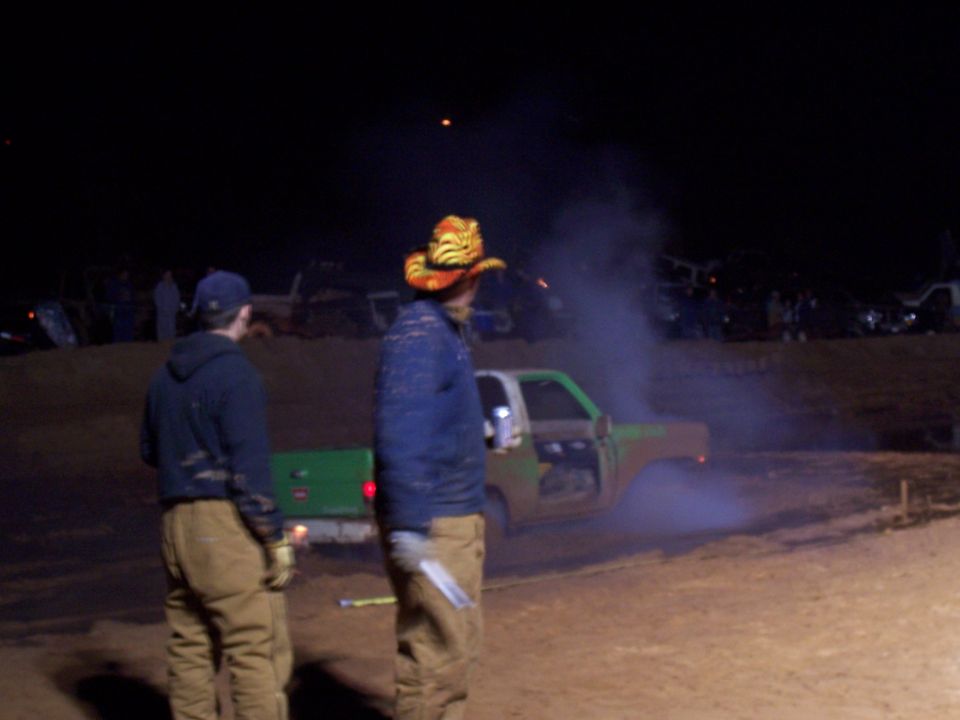 Side view of a green and brown truck emitting smoke at night