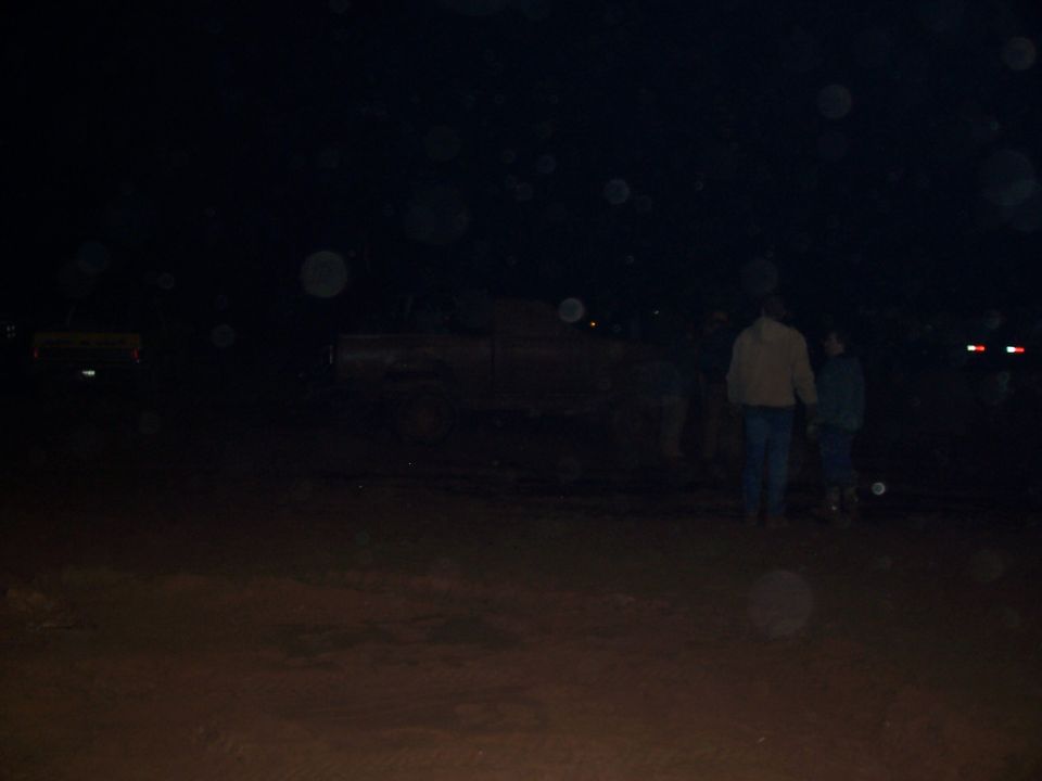 Truck in mud at night, two people standing nearby