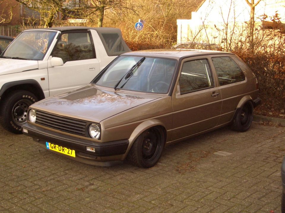 Brown Volkswagen Golf Mk2 with black wheels, lowered suspension, and a yellow license plate