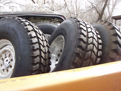 1979 Ford Bronco - Spare off-road tires are piled in the cargo area of a vehicle.